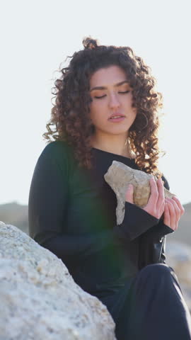 Beautiful young woman holding a rock in nature