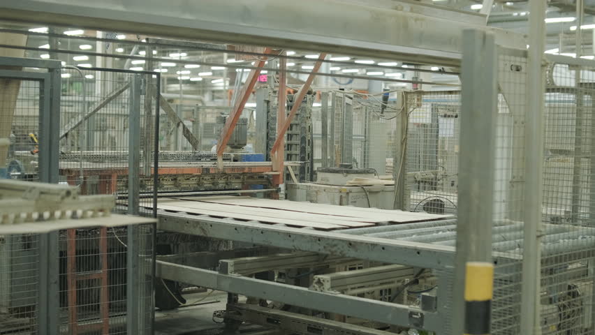 A stream of small wooden pieces and offcuts moving along a conveyor belt, representing byproduct management in a large wood factory