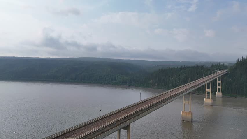 Aerial perspective slowly panning over the deh cho bridge crossing the vast mackenzie river in the northwest territories, canada, showcasing the remote wilderness and impressive engineering
