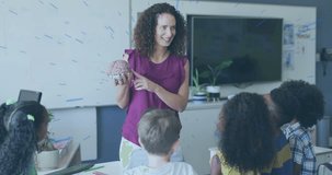 Female teacher holding brain model, pointing and turning sections while teaching classroom anatomy. Neuroscience, education, instructor, children, elementary, science, learning - Powered by Shutterstock - Get 15% off with code: PIKWIZARD15