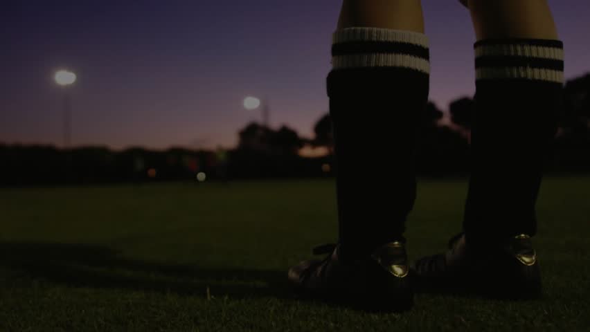 Goalkeeper holding ball at dusk lights coming on, overlay appearing right showing encryption for IT. Soccer, field, evening, glove, socks, striped, athlete