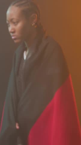Camera tightening woman wearing sport tee pulling flag and unfurling triband wrap in studio. Fabric, female, backdrop, orange, teal, editorial, vertical video