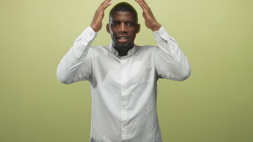 Man in white shirt with hands covering face and closed eyes in studio head in hands pose; stress anxiety exhaustion.