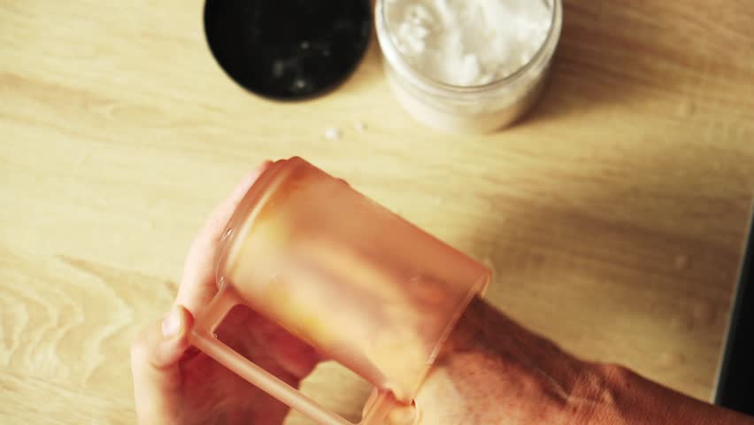 Person holds a clear container with a yellow sponge. The sponge is being pressed down by hands