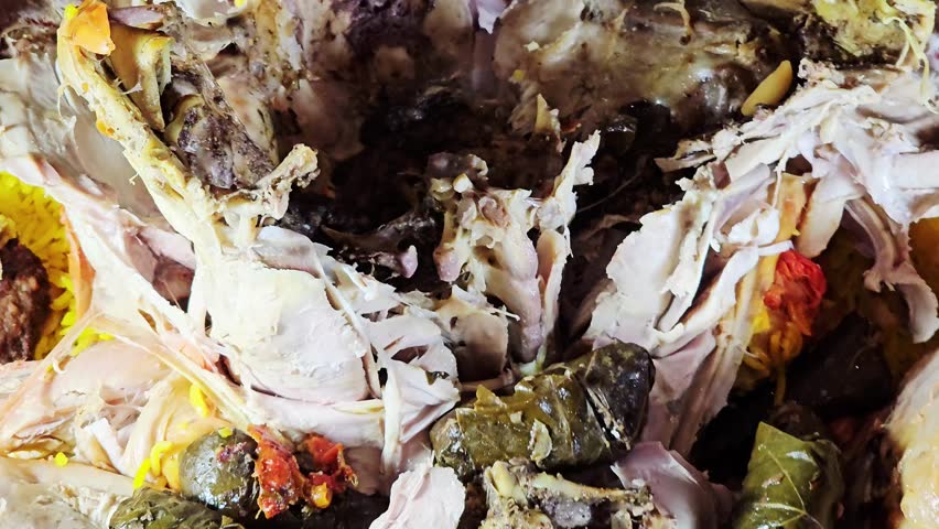 open Roasted turkey presented on a large serving tray over a bed of yellow basmati rice and garnished with orange slices and grilled Kofta meat skewers and stuffed dolma Mahshi wrapped grape leaves with rice, the turkey is cooked with spices Mandi style