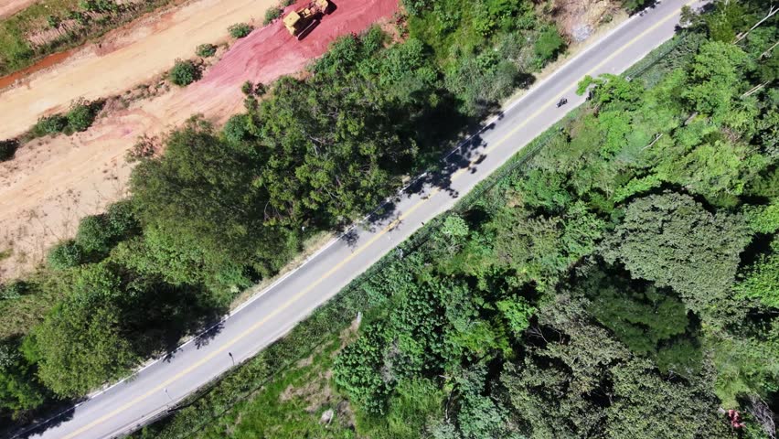 Aerial view of a tractor in a construction area beside a road with vehicles