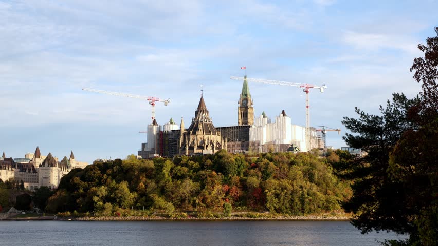 Parliament Hill across Ottawa River. Canadian government buildings under renovation in autumn landscape