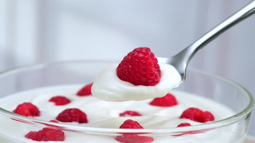 Raspberry yogurt in spoon, macro creamy dessert texture, fresh healthy breakfast