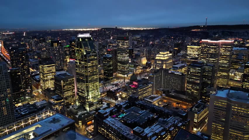 Aerial night view of Montreal downtown skyline with illuminated city lights, Quebec, Canada in 4K. Cinematic urban cityscape featuring skyscrapers and modern architecture, ideal for commercial use, travel and business concepts.