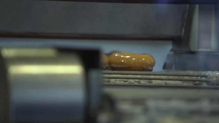 Fresh donut glistens under warm light as caramel glaze is applied in a bustling bakery. A sweet treat being crafted with care and precision for hungry customers. pastry industry food