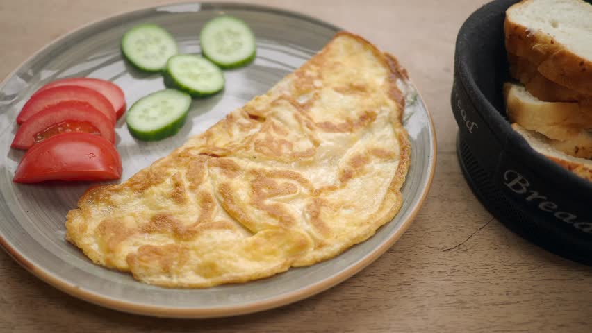 Delicious folded omelette with fresh tomato slices and cucumber. Served with bread. Morning breakfast.