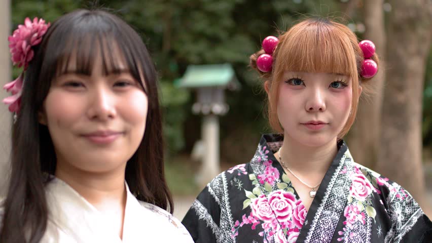 Low angle shot of two smiling Japanese women wearing traditional kimono at a shrine entrance