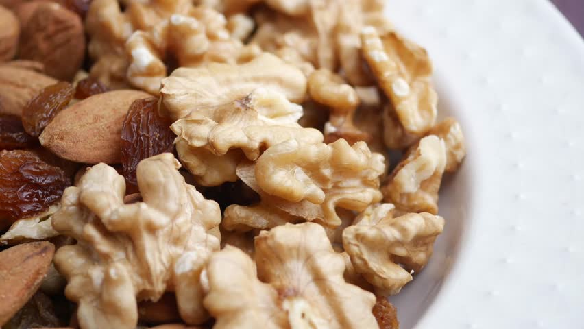 Healthy trail mix with walnuts almonds and raisins pile. Macro shot shows crunchy texture for organic snack.