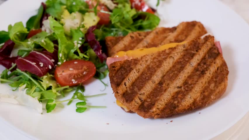 Rotating plate with grilled cheese and ham sandwich and fresh salad