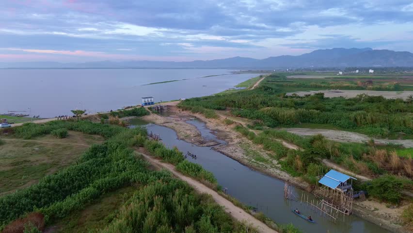 Aerial View of a Riverbank with Lush Greenery and Mountains