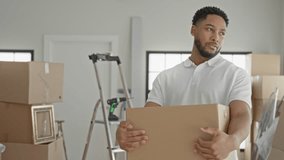Man holding a cardboard box with both hands and steady posture inside a building filled with packed moving boxes, ladder and framed art; moving day determined. - Powered by Shutterstock - Get 15% off with code: PIKWIZARD15