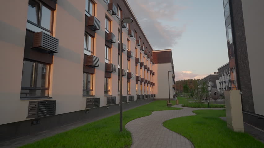 Sunlit Path In Peaceful Courtyard. Serene Outdoor Scene Featuring Glowing Windows And Lush Greenery. Stock Clip