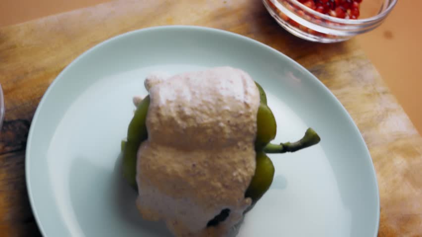 Carefully pouring sauce over the roasted pepper stuffed with filling