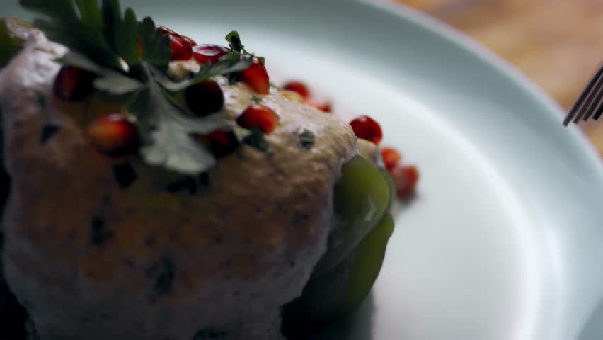 The stuffed Chiles Poblanos is sliced with a knife to reveal the filling