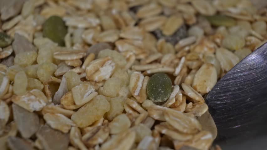 Extreme close up of a spoon scooping a mixture of granola and cereal grains