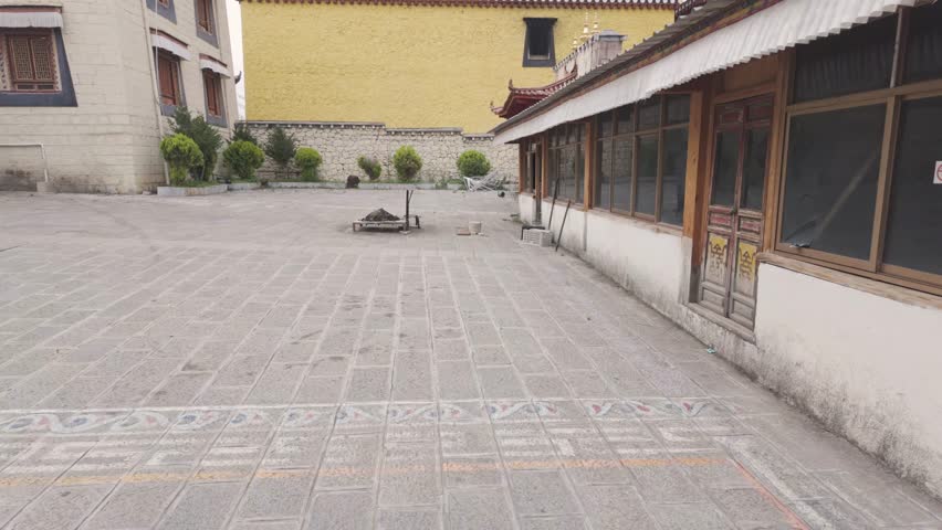 A wide shot showing the traditional Tibetan architecture and stone courtyard of the Ganden Sumtseling Monastery in Yunnan province.