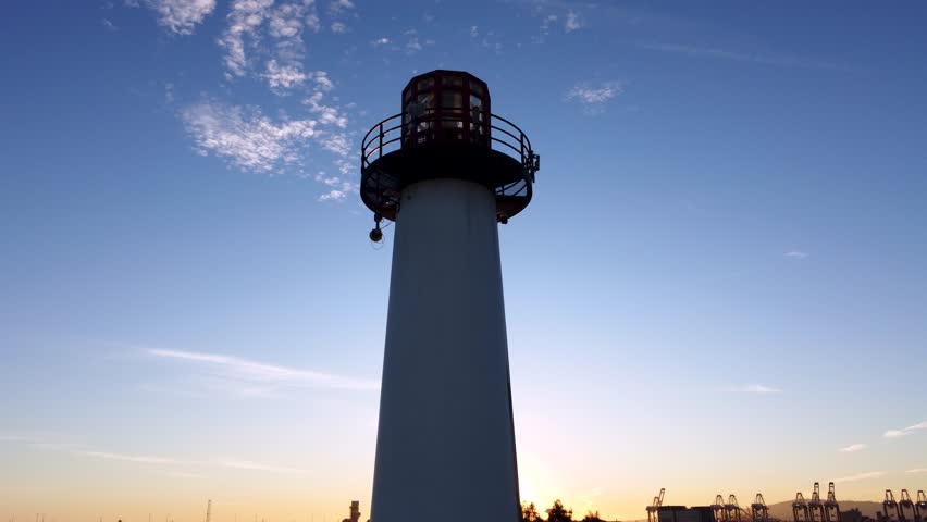 Lighthouse at Shipping Port During Sunset. Industrial port for shipping, import, export of cargo. Downtown Long Beach, Los Angeles, California. Cinematic Len Flare