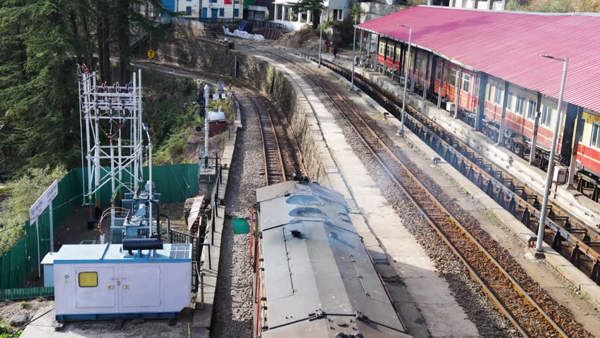 vintage mountain train stopping at hillside station with pine trees and railway signals