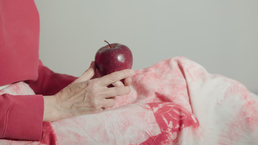 Holding a fresh red apple by a red dressed woman , healthy eating 