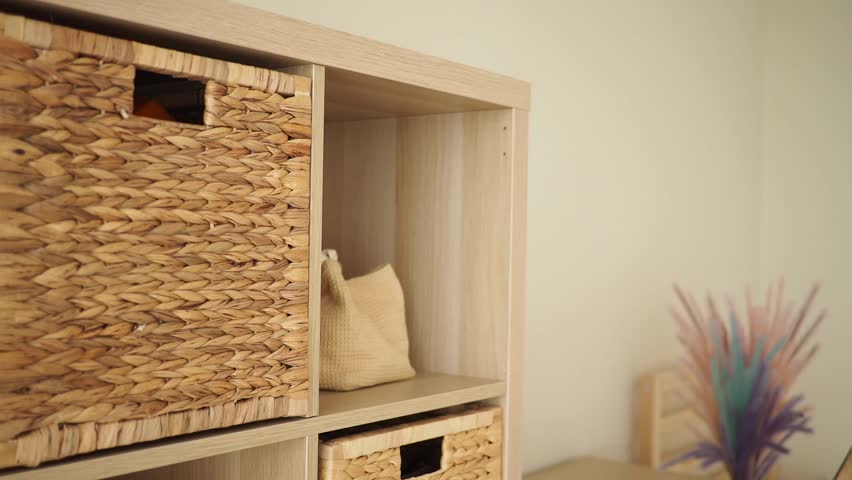 Close up shot of natural woven storage baskets and cubes on a light wood shelf. Home decor and organization.