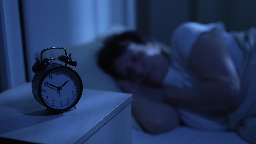 Elderly woman sleeping at night with clock nearby showing time