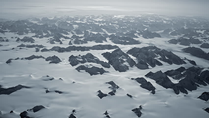 Aerial view of Greenland glacier landscape from above, vast frozen mountains and ice fields stretching across remote Arctic wilderness