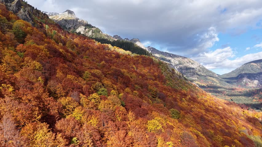 Oblique aerial landscape showing colorful fall trees, rocky slopes, and a broad mountain valley.