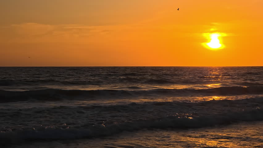 Santa Monica sunset over Pacific Ocean with golden sky and shimmering waves, calm coastal seascape at evening in California