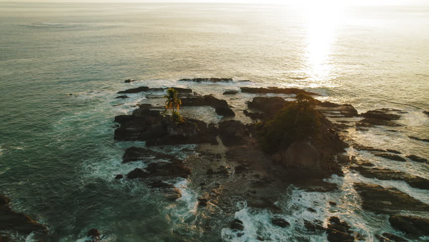 Rocky islet with lone palm at sunset on Costa Rica Pacific coast