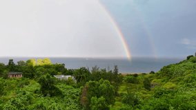 Stunning Double Rainbow Over Ocean and Greenery, Rare sight of a double rainbow stretching over lush green hills after rain. - Powered by Shutterstock - Get 15% off with code: PIKWIZARD15