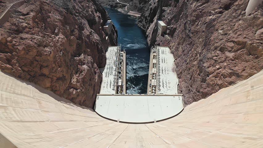 View from top of Hoover Dam looking down into Colorado River channel between canyon walls, dramatic perspective of hydroelectric structure