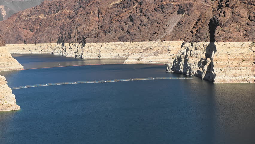 Lake Mead water levels with rocky canyon shoreline in Mojave Desert, calm reservoir surface and geological formations in Nevada Arizona
