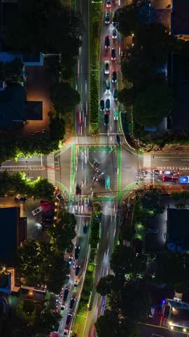 Top-down aerial timelapse of night traffic at busy intersection in Jakarta, Indonesia. Cars create dynamic light trails on urban crossroads showing city transport, motion and congestion.