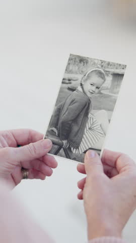 Hands, photograph and memory for childhood in home for nostalgia, relax and senior person in retirement. Elderly woman, remember and vintage picture with monochrome, girl and daydream at apartment
