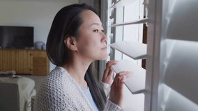 Woman adjusting blind slat by window, peering out while digital code, circuitry surging then fading. Contemplative, livingroom, female, pane, shades, overlay, graphics - Powered by Shutterstock - Get 15% off with code: PIKWIZARD15