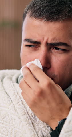 Man, tissue and sick with blanket in home with flu, mucus and virus with fatigue, chills or stress. Person, tired and rest with recovery, healing or cleaning nose for cold, cover and break at house