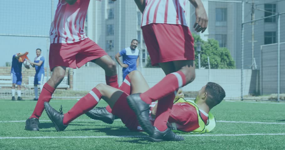 Player in yellow bib lying on turf after physical play, teammates checking for sports injury. Athletes, training, photorealistic, soccer, urban, outdoor, pitch