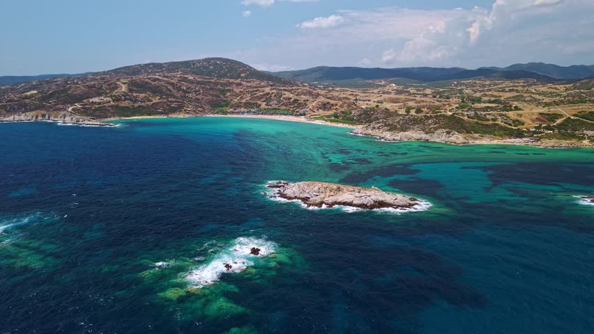Aerial view of the pristine sandy shore and crystal clear turquoise sea at Kriaritsi beach on a sunny summer day in Sithonia, Chalkidiki, Greece