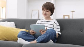 Cute boy using tablet on sofa at home - Powered by Shutterstock - Get 15% off with code: PIKWIZARD15