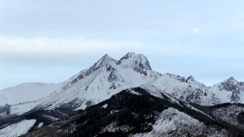 Aerial view of a mountain range during sunrise and covered in snow. 