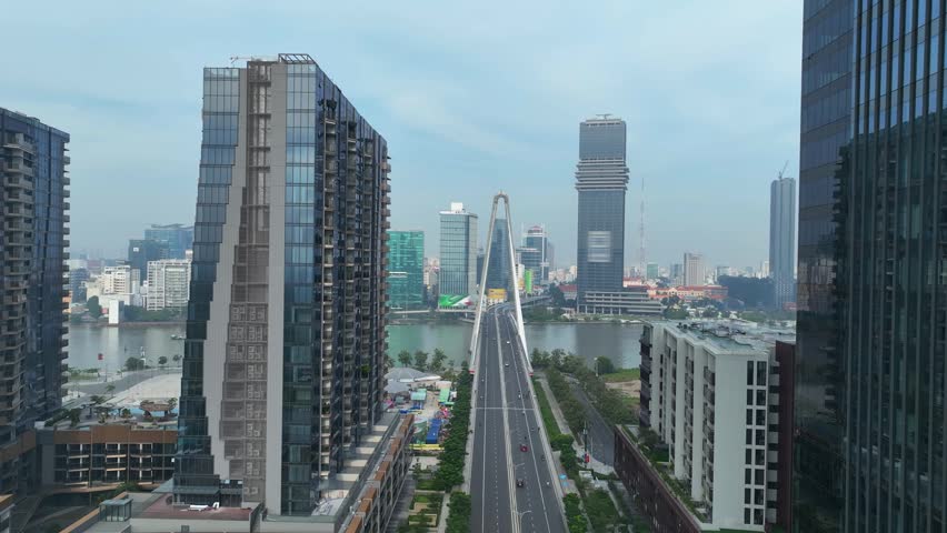 Frontal urban view of long boulevard aligned with landmark bridge and skyline, emphasizing symmetry and modern architecture in Saigon cityscape.