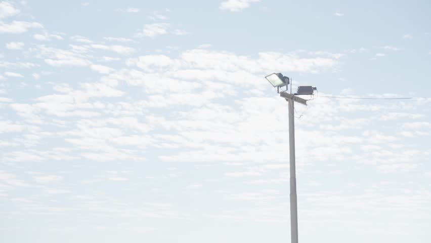 Light pole against blue sky in a parking lot.
