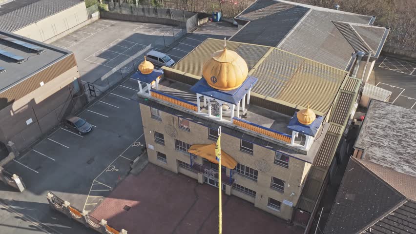 Guru Nanak Gurdwara Sikh temple on Halifax Old Road Huddersfield Kirklees West Yorkshire England United Kingdom with golden domes and Nishan Sahib flag, drone orbit shot