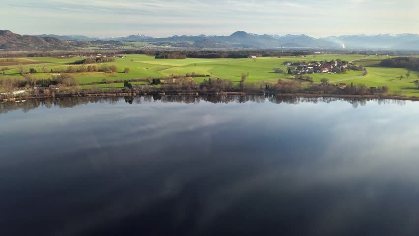Aerial view of abtsee lake surrounded by fields and forest near mountains in Germany, calm winter landscape with soft light.