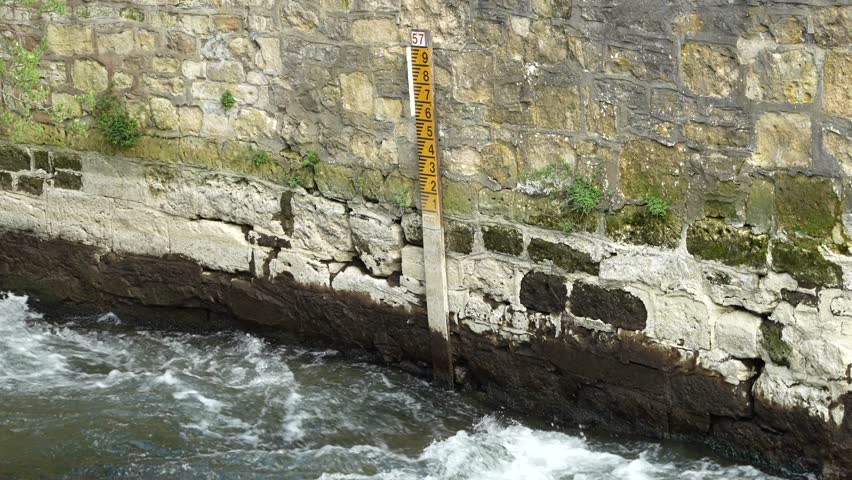 Water level marker on stone wall, above fast flowing river in England